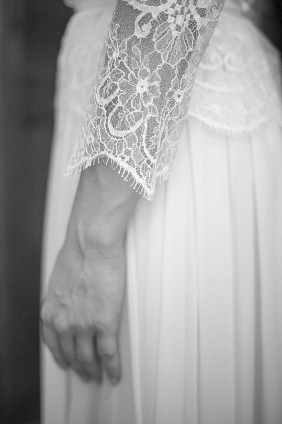 Détail d'une manche de robe de mariée en dentelle. L a photo est en noir et blanc